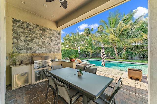 view of patio / terrace with an outdoor kitchen, ceiling fan, sink, grilling area, and a fenced in pool