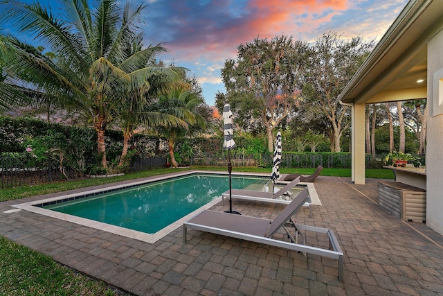 pool at dusk with a patio area