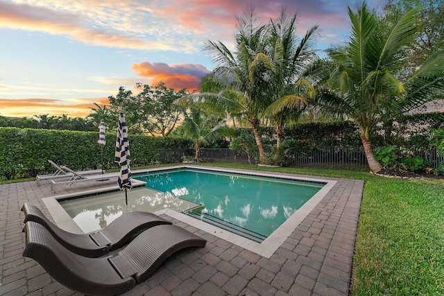 pool at dusk featuring a patio area