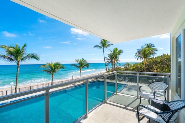 view of swimming pool with a water view and a beach view