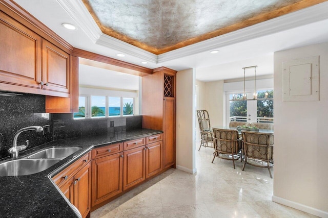 kitchen with electric panel, dark stone counters, sink, backsplash, and pendant lighting