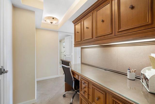 office with built in desk and a tray ceiling