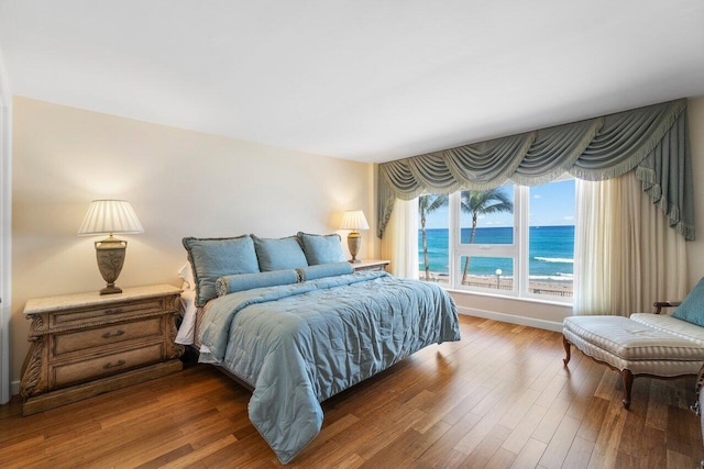 bedroom featuring dark hardwood / wood-style flooring and a water view