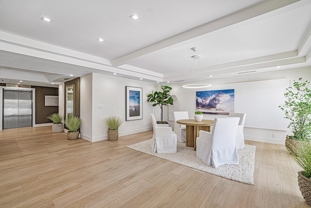 unfurnished dining area featuring elevator, light hardwood / wood-style flooring, and a raised ceiling