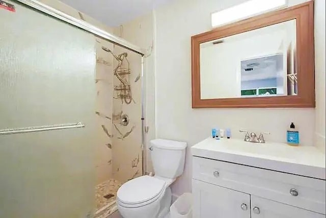 bathroom featuring vanity, toilet, and a shower with shower door