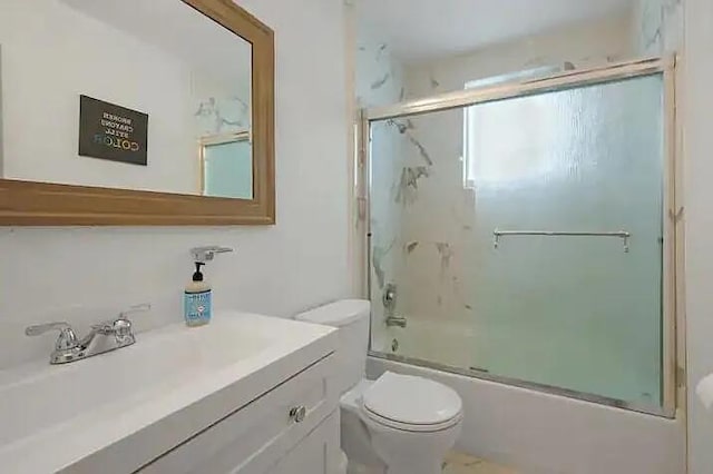 full bathroom featuring vanity, combined bath / shower with glass door, and toilet