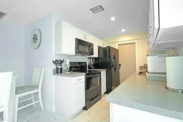 kitchen with black appliances, light stone countertops, a breakfast bar area, and white cabinets