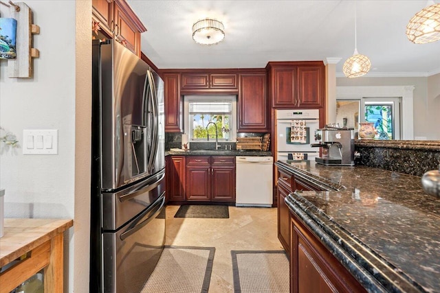 kitchen featuring white appliances, dark stone counters, sink, crown molding, and decorative light fixtures