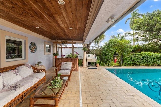 view of pool featuring an outdoor living space, a patio, and ceiling fan