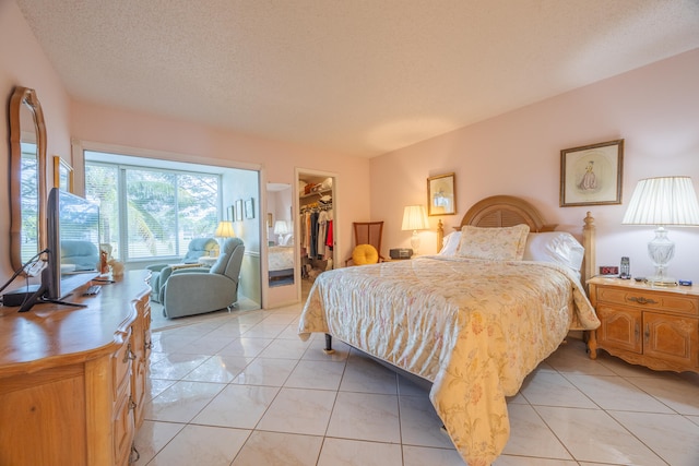 bedroom with a textured ceiling, a spacious closet, a closet, and light tile patterned flooring