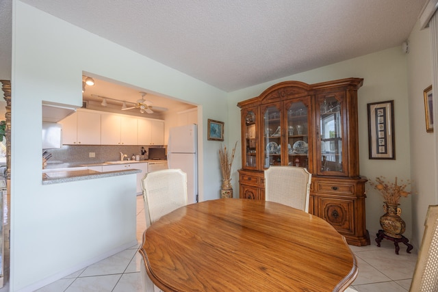 dining space featuring ceiling fan, light tile patterned floors, and a textured ceiling