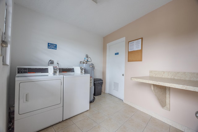 laundry room with separate washer and dryer, light tile patterned floors, and water heater