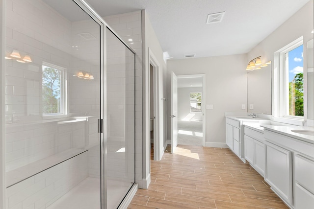 bathroom featuring a textured ceiling, vanity, and walk in shower