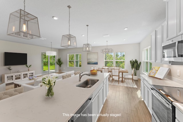 kitchen featuring white cabinets, decorative light fixtures, stainless steel appliances, and a healthy amount of sunlight