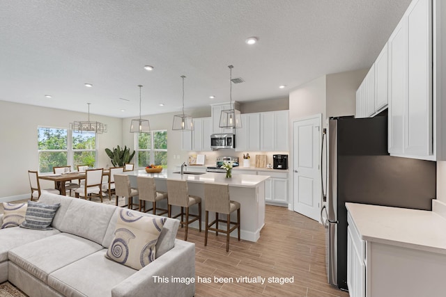 living room featuring sink, a textured ceiling, and light hardwood / wood-style flooring