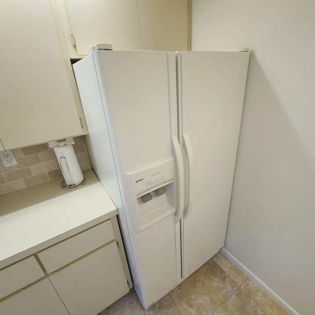 interior details with white fridge with ice dispenser, backsplash, and light tile patterned flooring