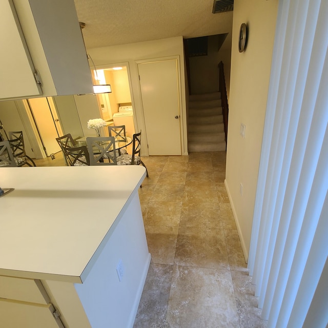 hall with washer / dryer and a textured ceiling