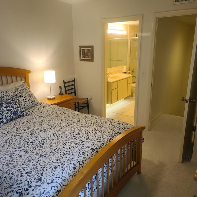 carpeted bedroom with ensuite bath and sink