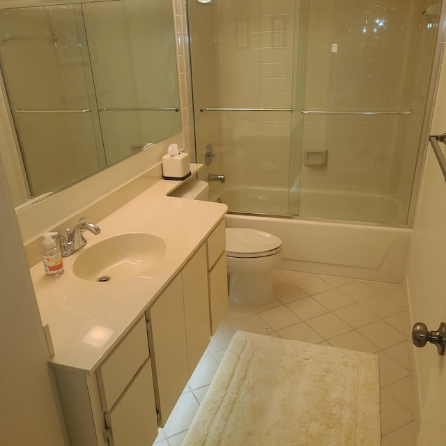 full bathroom featuring vanity, bath / shower combo with glass door, tile patterned flooring, and toilet