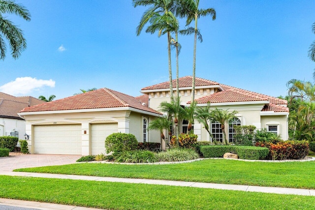 mediterranean / spanish home featuring a garage and a front yard