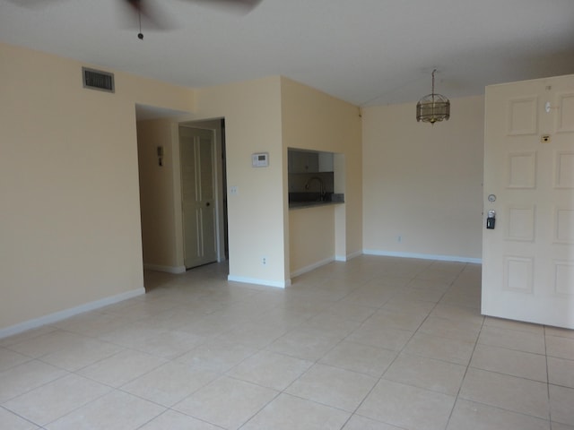 tiled empty room with ceiling fan with notable chandelier