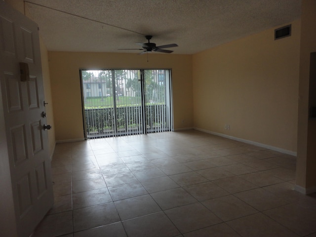 spare room featuring ceiling fan, tile patterned floors, and a textured ceiling