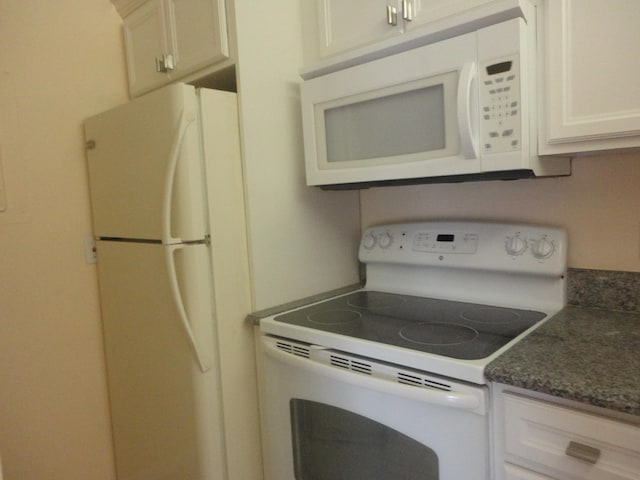 kitchen featuring white cabinets, white appliances, and dark stone counters