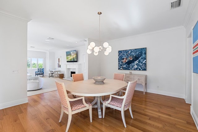 dining room with an inviting chandelier, light hardwood / wood-style flooring, and crown molding