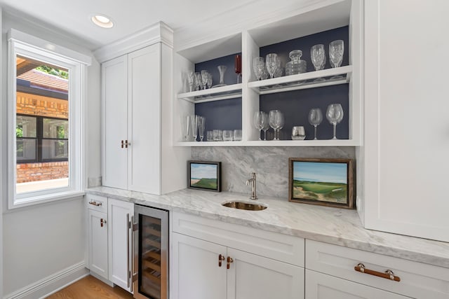 bar with a healthy amount of sunlight, light stone countertops, white cabinetry, and beverage cooler