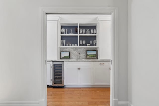 bar featuring white cabinetry, sink, beverage cooler, and light hardwood / wood-style flooring