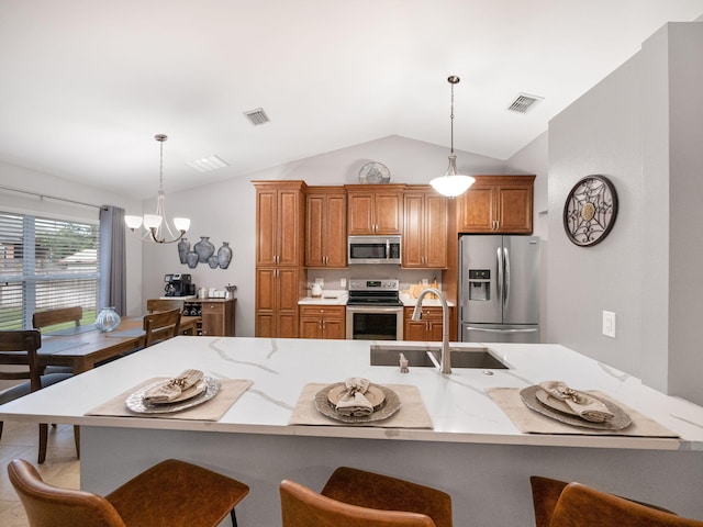 kitchen featuring sink, decorative light fixtures, vaulted ceiling, and stainless steel appliances