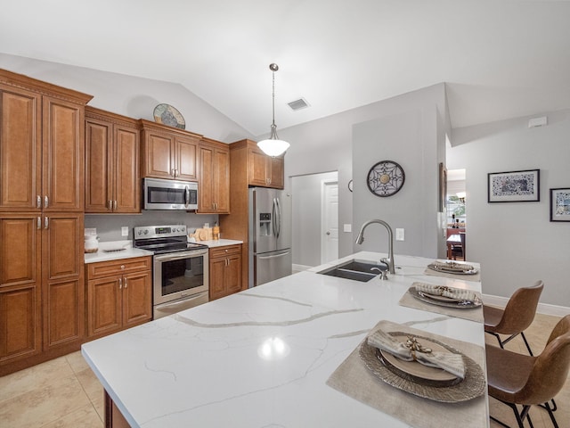 kitchen with lofted ceiling, decorative light fixtures, stainless steel appliances, an island with sink, and sink