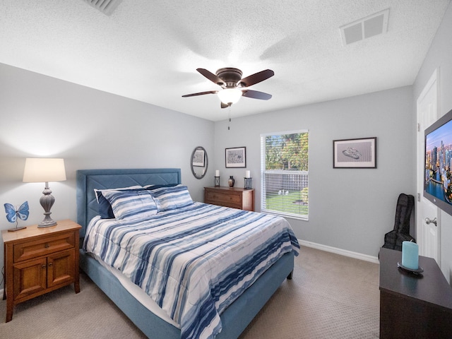 bedroom featuring ceiling fan, a textured ceiling, and light carpet