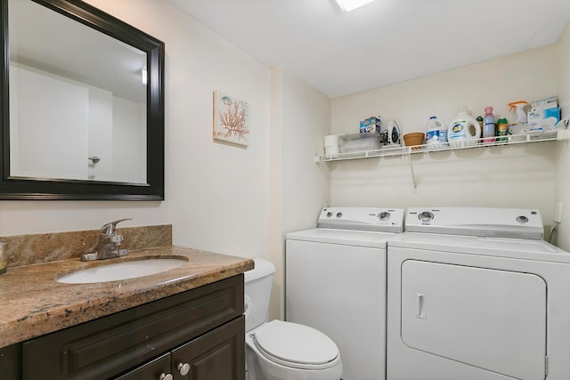 bathroom with washer and dryer, toilet, and vanity