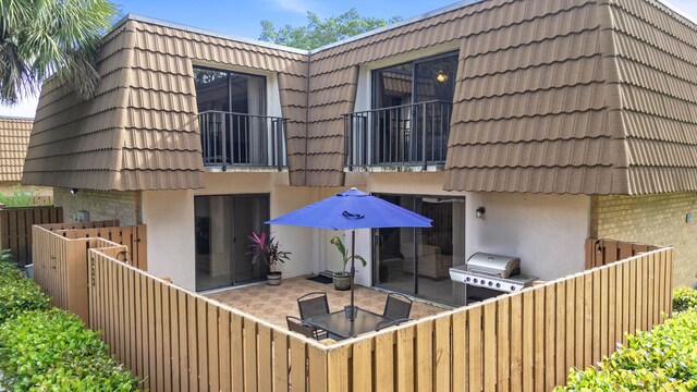233 Charter Way, West Palm Beach, FL 33407 - back of property with a balcony, mansard roof, a tiled roof, stucco siding, and a patio
