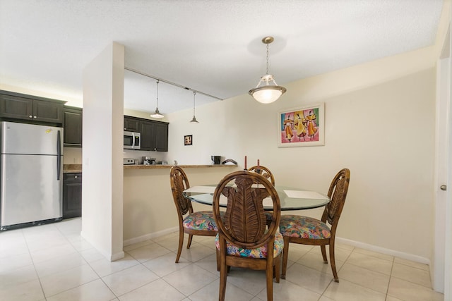 tiled dining room featuring rail lighting and a textured ceiling