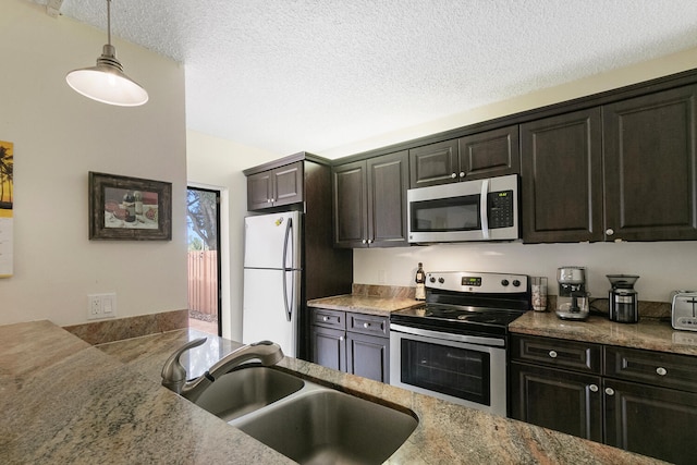 kitchen featuring appliances with stainless steel finishes, a textured ceiling, sink, decorative light fixtures, and stone countertops