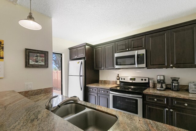 233 Charter Way, West Palm Beach, FL 33407 - kitchen with stainless steel appliances, a sink, decorative light fixtures, a textured ceiling, and stone counters