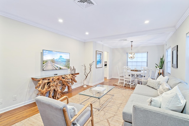 living room with light hardwood / wood-style flooring, crown molding, and an inviting chandelier