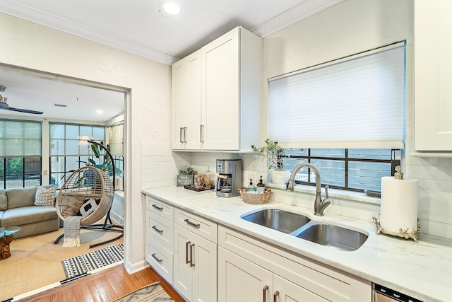 kitchen featuring light hardwood / wood-style floors, sink, ornamental molding, tasteful backsplash, and white cabinets