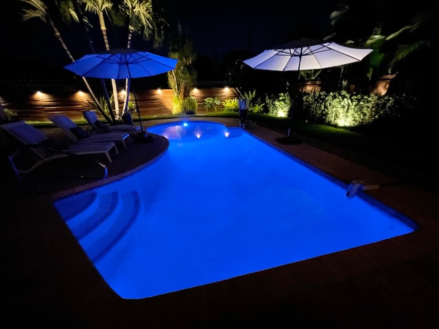 pool at night featuring a water view