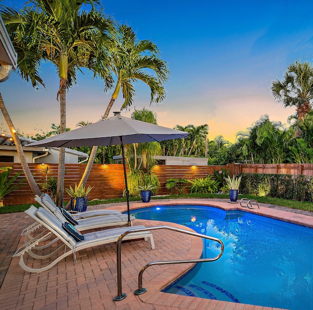 pool at dusk featuring a patio area