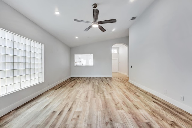 spare room with a healthy amount of sunlight, light wood-type flooring, and lofted ceiling