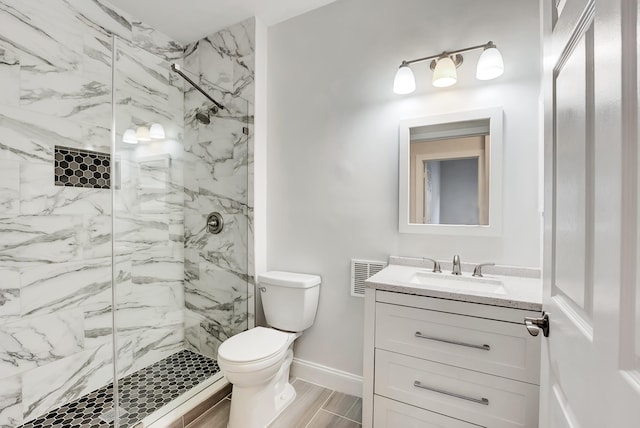 bathroom with vanity, toilet, and tiled shower