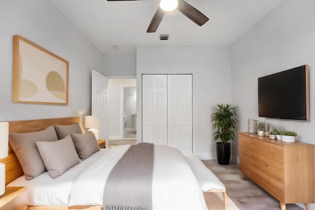 bedroom featuring light hardwood / wood-style floors, ceiling fan, connected bathroom, and a closet