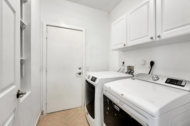 laundry room featuring light parquet flooring, cabinets, and washing machine and clothes dryer