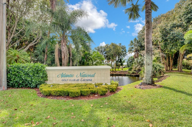 community / neighborhood sign with a lawn and a water view