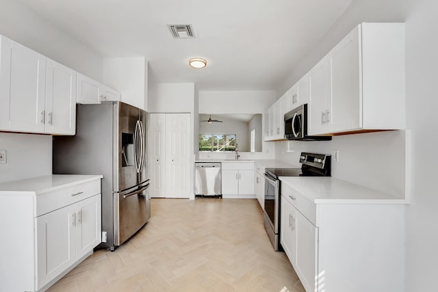 kitchen featuring light parquet floors, stainless steel appliances, white cabinetry, sink, and ceiling fan