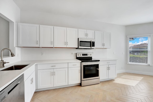 kitchen featuring light parquet flooring, white cabinetry, appliances with stainless steel finishes, and sink