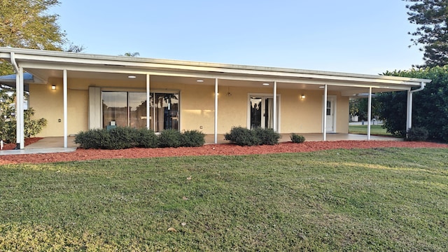 back of property with a yard and a patio